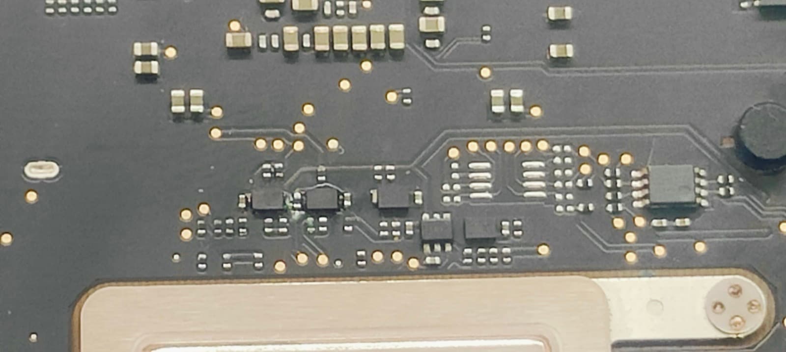 Magnified view of the charging and power management section of a MacBook Pro 14-inch A2442 logic board during chip-level micro-soldering repair
